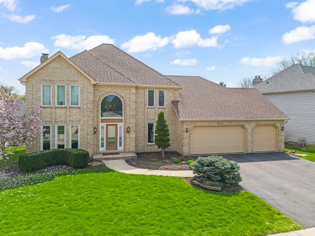 view of front of house featuring asphalt driveway, an attached garage, brick siding, and a front yard