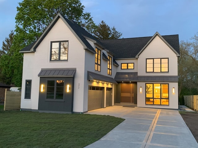 rear view of house with a garage, driveway, a standing seam roof, a shingled roof, and a yard