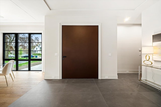 foyer featuring dark tile patterned flooring and baseboards