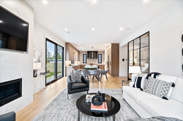 living area with light wood-style floors, recessed lighting, and a glass covered fireplace