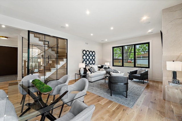 living area with recessed lighting, baseboards, light wood-type flooring, visible vents, and stairway