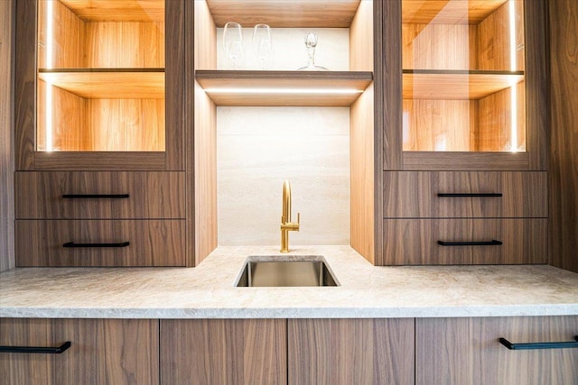 kitchen with a sink, modern cabinets, and light stone countertops