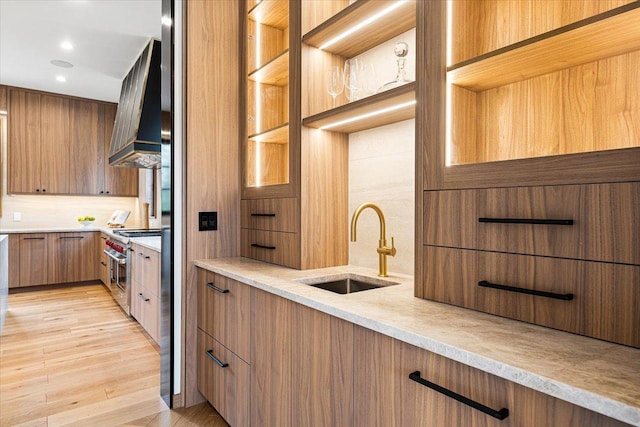 kitchen with glass insert cabinets, modern cabinets, custom range hood, a sink, and stainless steel range