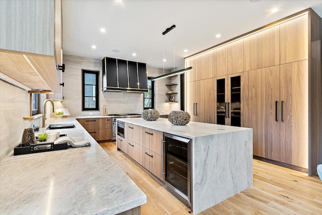 kitchen featuring wall chimney range hood, a sink, a large island, wine cooler, and modern cabinets