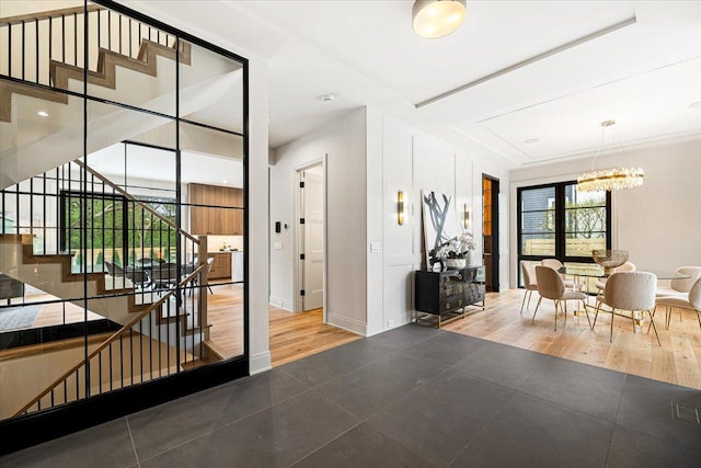 tiled entryway featuring baseboards, stairs, and a notable chandelier