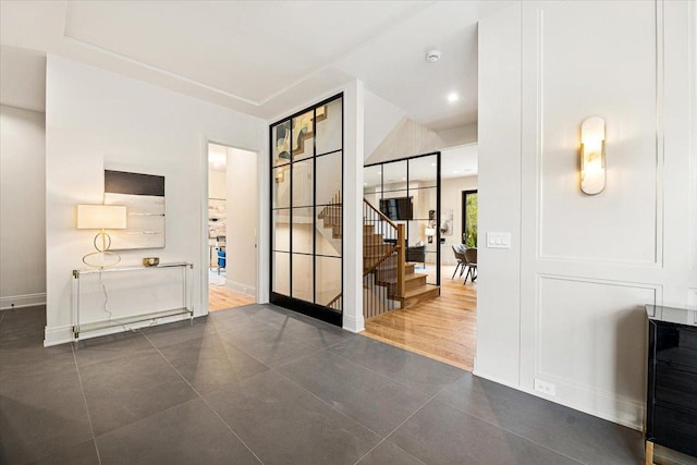 hallway featuring stairs, dark tile patterned floors, and baseboards