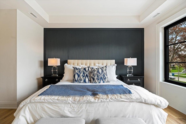 bedroom with multiple windows, wood finished floors, and visible vents