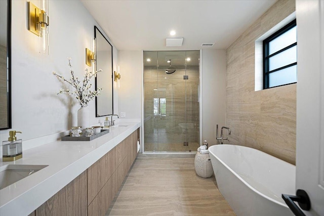 full bathroom with a sink, double vanity, visible vents, a soaking tub, and a stall shower