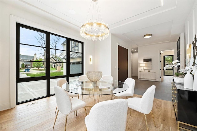 dining area with baseboards, visible vents, an inviting chandelier, and light wood finished floors