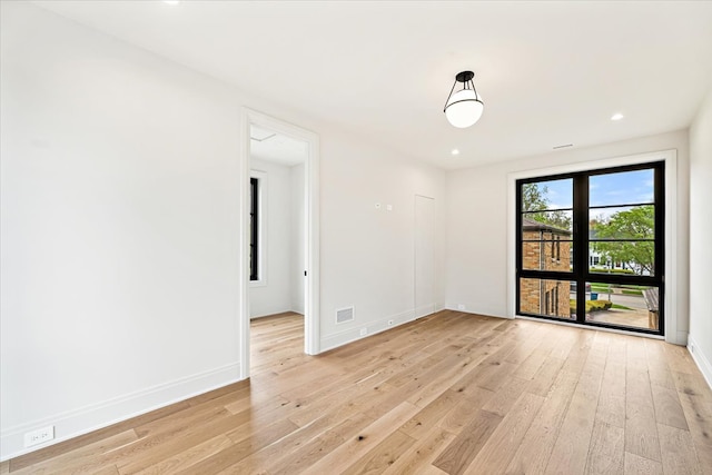 empty room with light wood-style floors, recessed lighting, baseboards, and visible vents