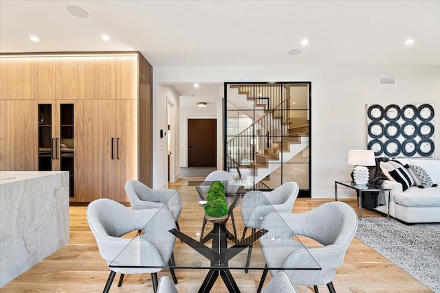 living area featuring recessed lighting, visible vents, light wood finished floors, and stairway