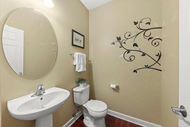 bathroom featuring toilet, baseboards, a sink, and wood finished floors