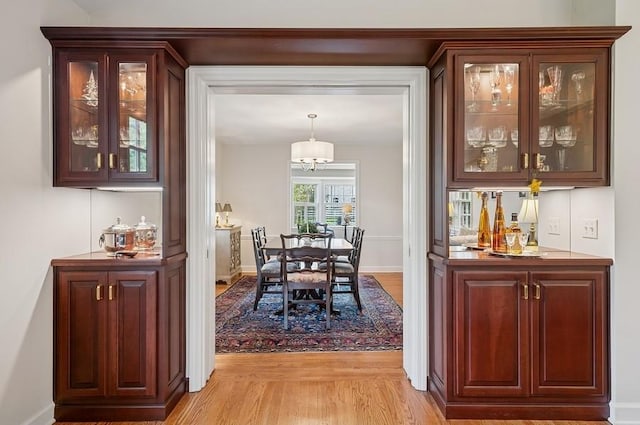 dining room featuring a dry bar, light wood-style floors, and baseboards