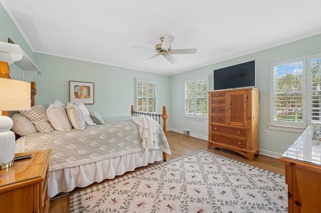 bedroom featuring multiple windows, wood finished floors, baseboards, and crown molding