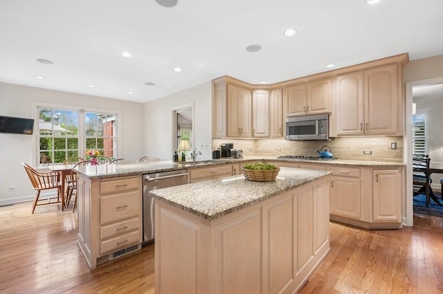kitchen with light wood-style flooring, light brown cabinets, a wealth of natural light, and appliances with stainless steel finishes