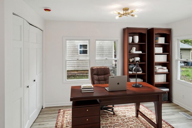 office space with baseboards, visible vents, and light wood-type flooring