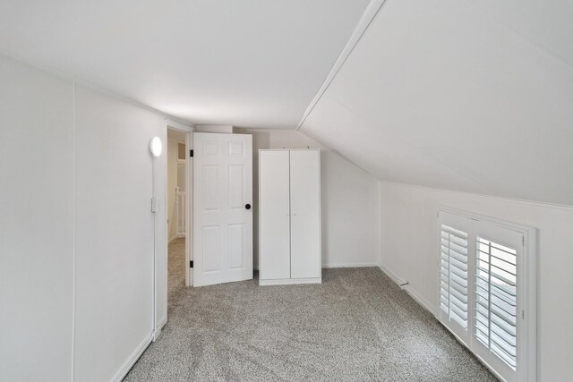 additional living space featuring carpet flooring and lofted ceiling
