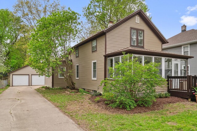 view of front of house featuring an outdoor structure, a garage, a sunroom, and a chimney