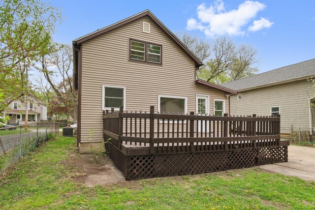 rear view of property featuring a lawn, fence, and a wooden deck