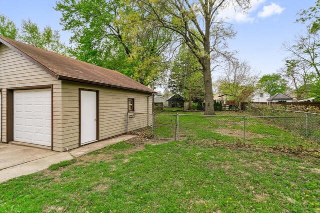 view of yard with concrete driveway, fence, an outbuilding, and a garage