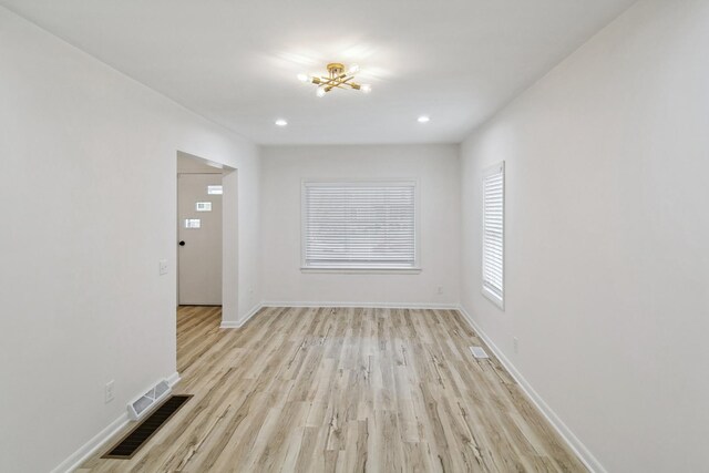 unfurnished living room with an inviting chandelier, baseboards, recessed lighting, and light wood-type flooring