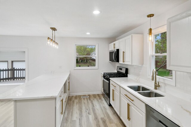 kitchen with appliances with stainless steel finishes, tasteful backsplash, a sink, a peninsula, and light wood-type flooring