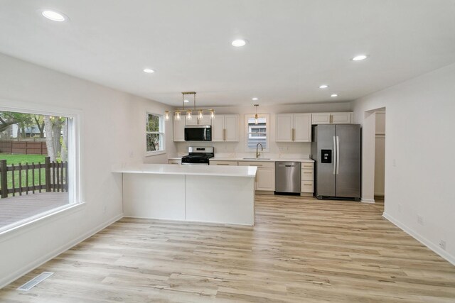 kitchen featuring light countertops, a sink, appliances with stainless steel finishes, and light wood-style flooring