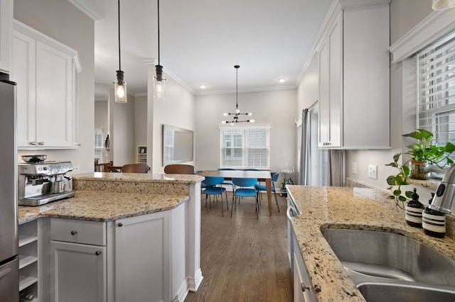 kitchen with a sink, dark wood-style flooring, white cabinetry, a chandelier, and crown molding