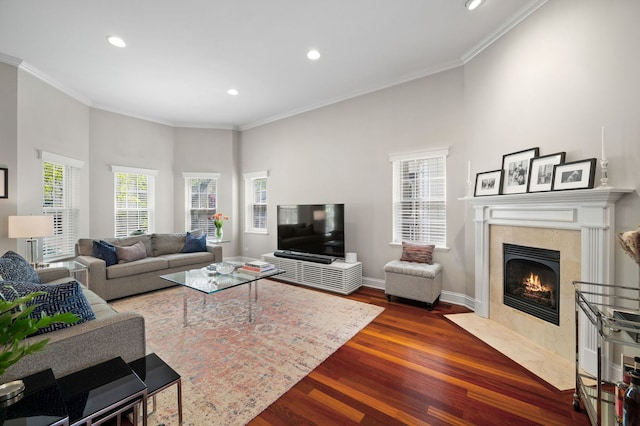 living area featuring dark wood finished floors, ornamental molding, recessed lighting, a premium fireplace, and baseboards