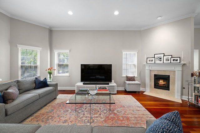 living room featuring wood finished floors, a tile fireplace, ornamental molding, recessed lighting, and baseboards