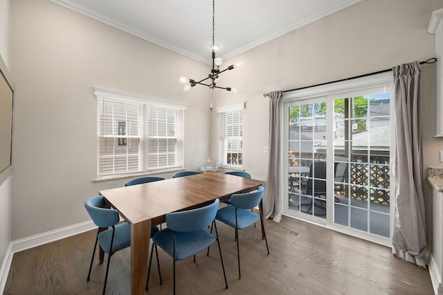 dining space featuring a chandelier, ornamental molding, wood finished floors, and baseboards