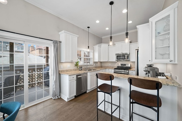 kitchen with stainless steel appliances, a sink, a peninsula, white cabinets, and crown molding