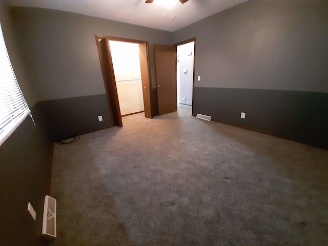 carpeted empty room featuring visible vents and ceiling fan