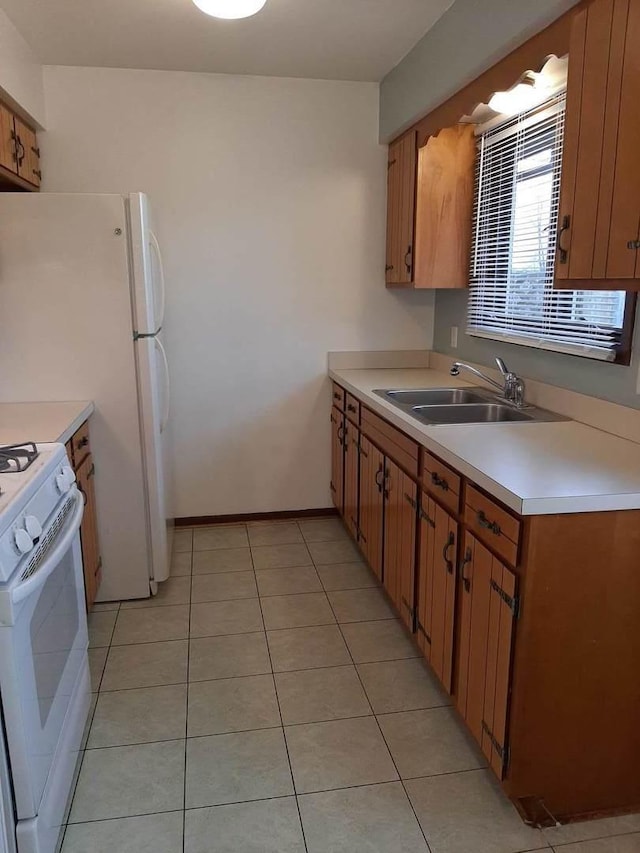 kitchen with light countertops, gas range gas stove, light tile patterned flooring, and a sink