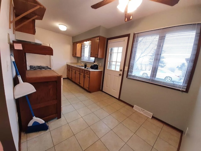 kitchen with a ceiling fan, light tile patterned flooring, a sink, visible vents, and light countertops