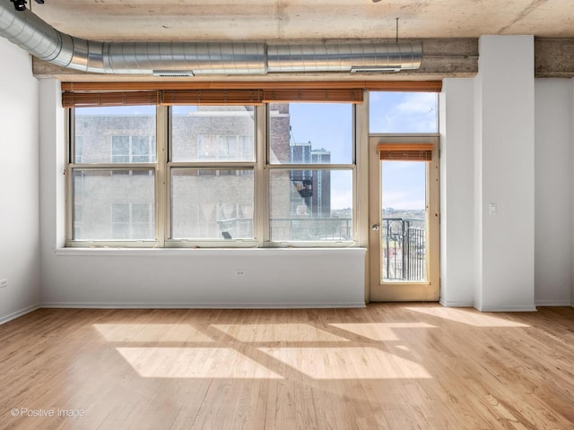 empty room with a healthy amount of sunlight, baseboards, and wood finished floors