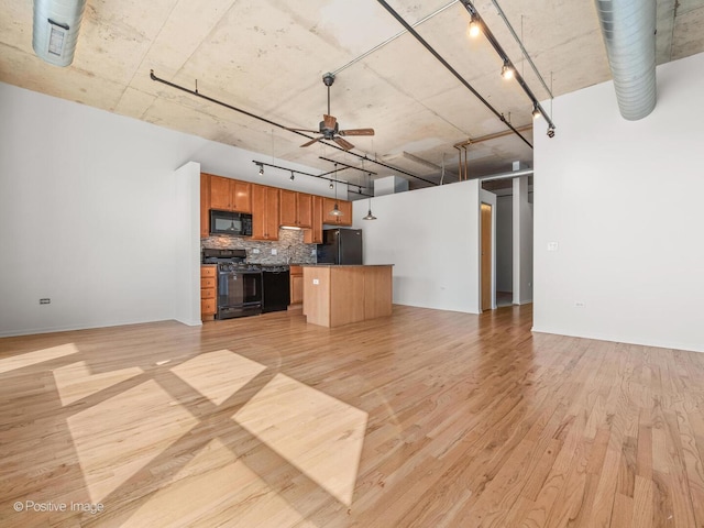 unfurnished living room featuring rail lighting, light wood-style flooring, and ceiling fan
