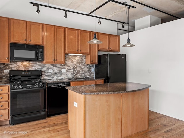 kitchen with track lighting, a center island, light wood finished floors, backsplash, and black appliances