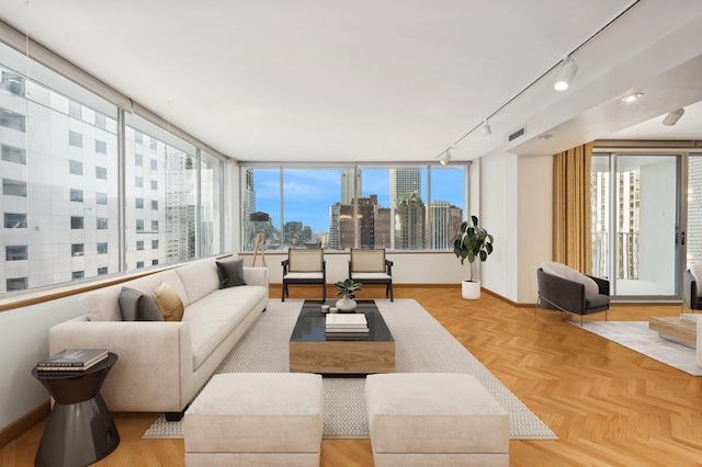living area with track lighting, baseboards, a city view, and visible vents