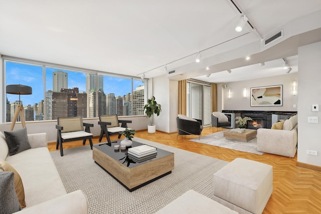 living room featuring visible vents, track lighting, a city view, and a glass covered fireplace