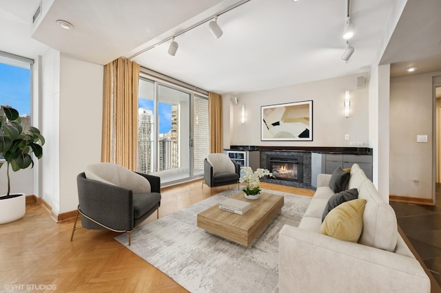 living room with baseboards, rail lighting, visible vents, and a fireplace