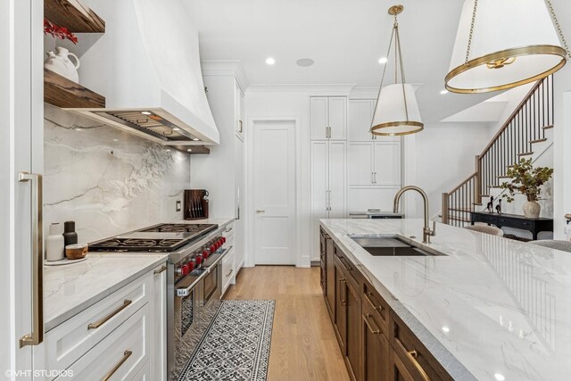 1934 W Patterson Ave, Chicago, IL 60613 - kitchen with range with two ovens, a sink, custom range hood, white cabinets, and light wood-style floors