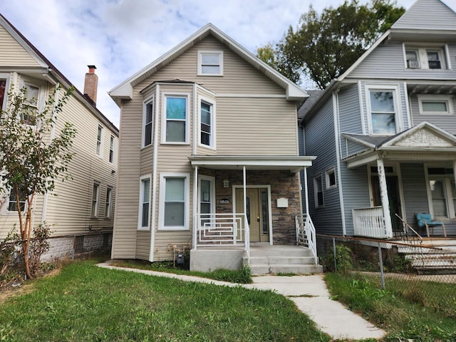 11947 S Eggleston Ave, Chicago, IL 60628 - view of front of home featuring a porch, fence private yard, stone siding, and a front lawn