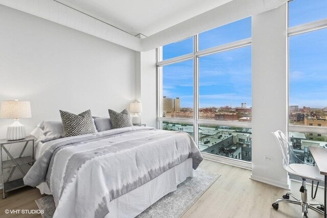bedroom with a city view, floor to ceiling windows, and wood finished floors