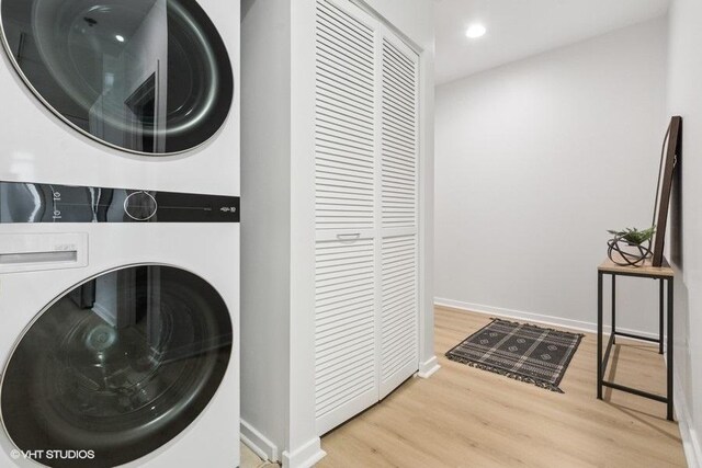 laundry area with laundry area, recessed lighting, stacked washer / dryer, and wood finished floors