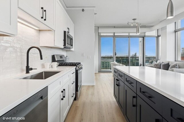 kitchen featuring decorative backsplash, appliances with stainless steel finishes, a sink, light countertops, and white cabinets