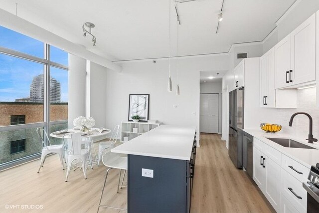kitchen with track lighting, a sink, light wood finished floors, and light countertops
