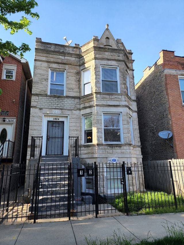 3824 W Grenshaw St, Chicago, IL 60624 - view of front of house featuring stone siding, a fenced front yard, and a gate