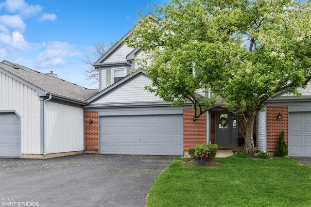 view of front of house featuring brick siding, an attached garage, driveway, and a front yard