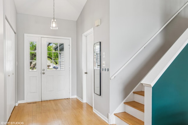 foyer entrance featuring baseboards, light wood-style flooring, stairs, and visible vents